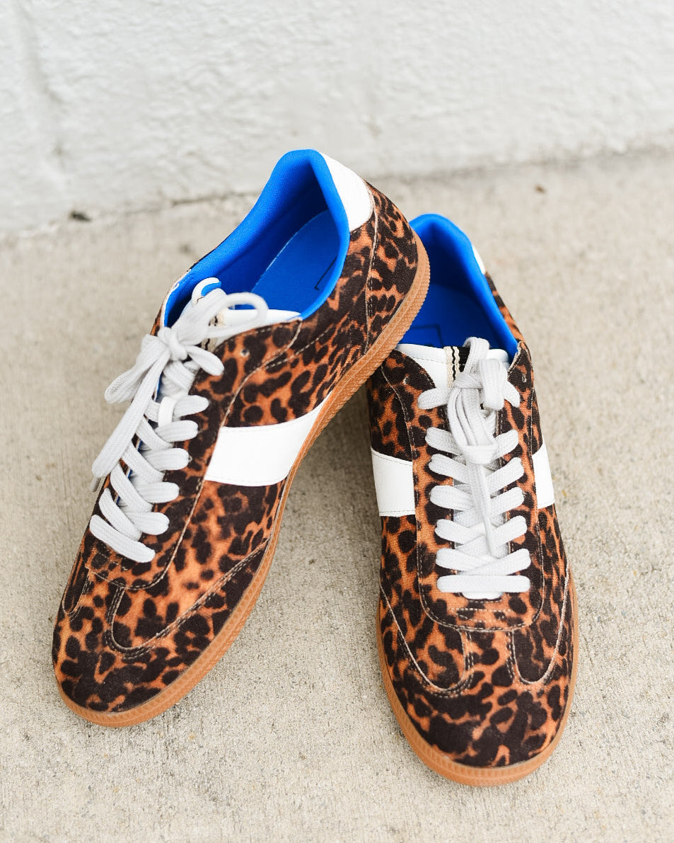 Leopard print sneakers with blue accents on a concrete surface.