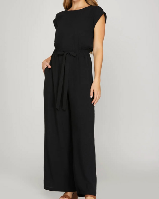 Woman wearing a black sleeveless jumpsuit on a gray background