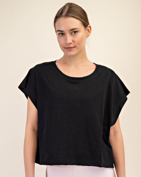Woman wearing a black top and pink pants on a beige background