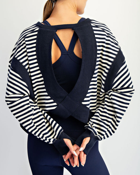 Woman wearing a black and white striped cardigan over a dark top on a light gray background